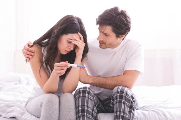 Couple dreaming to be parents. Upset man comforting his depressed wife with negative pregnancy test, free space